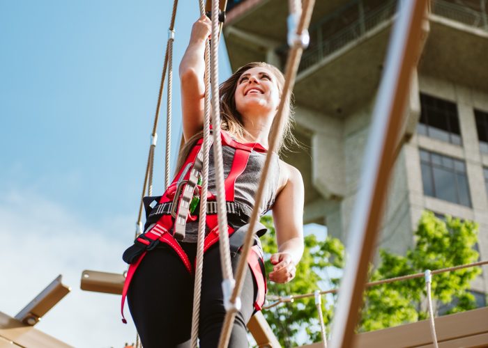 Girl on ropes course with tower behind her